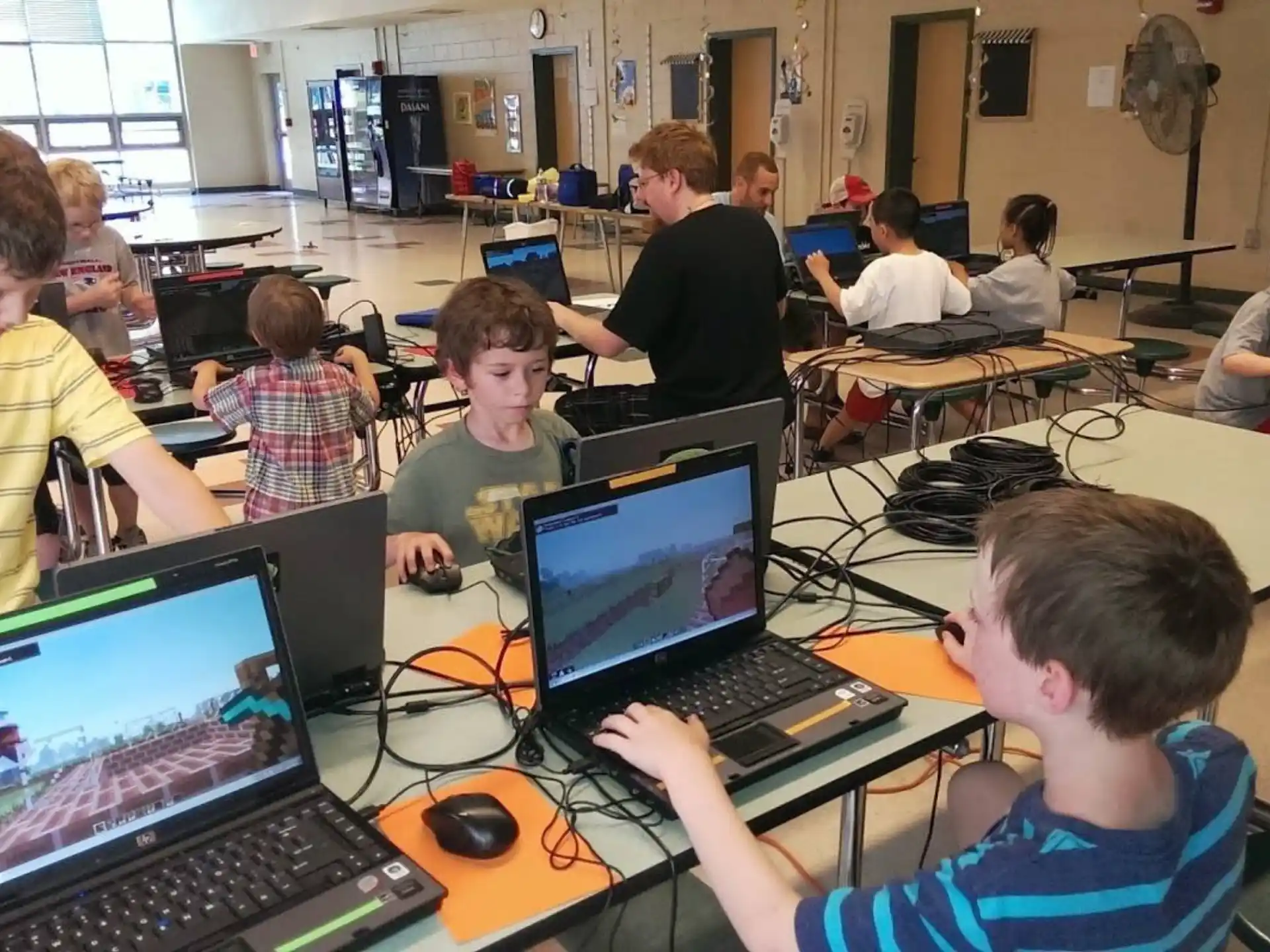 a group of people sitting at desks with laptops