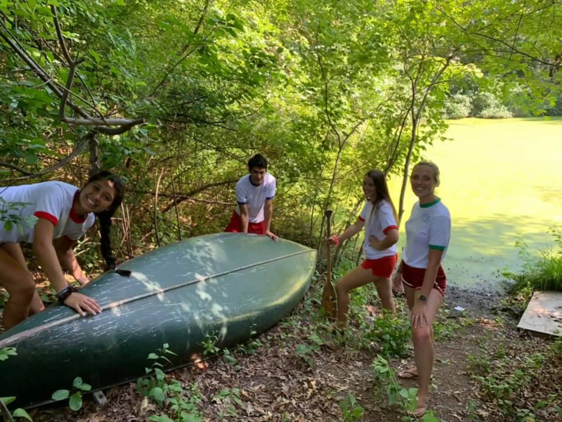 a group of people standing around a boat on a river bank
