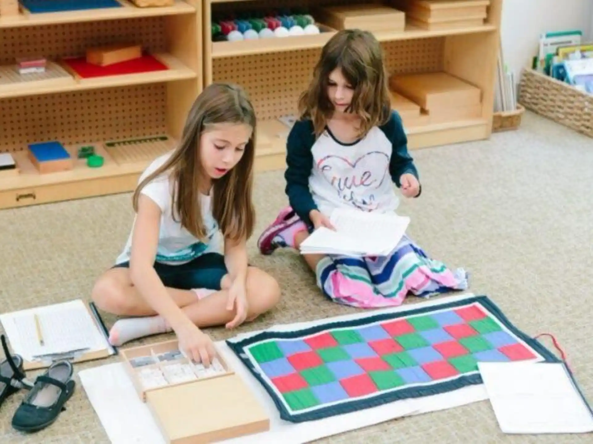a couple of girls sitting on the floor reading books