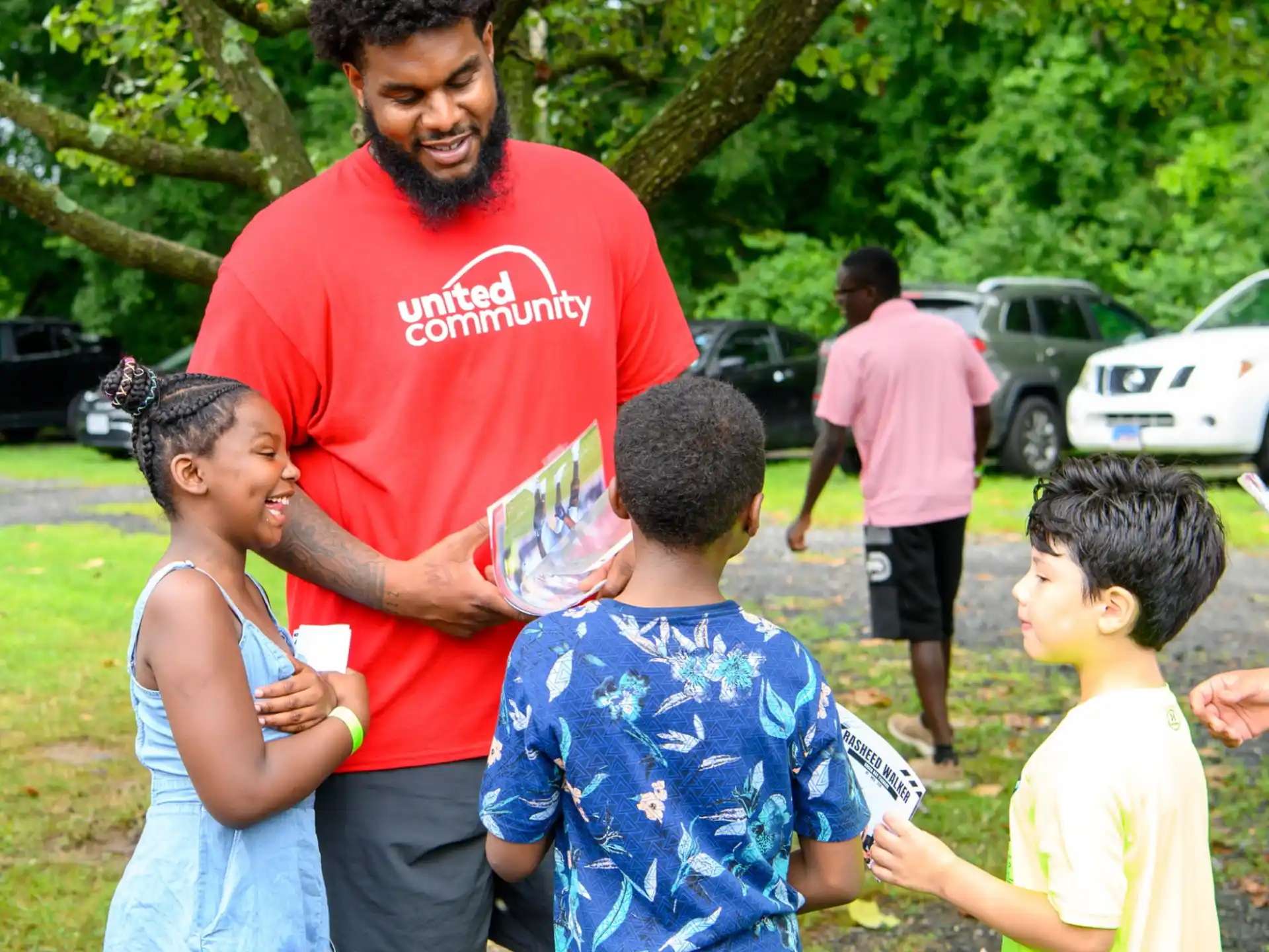 a man holding a bottle of water with kids around him