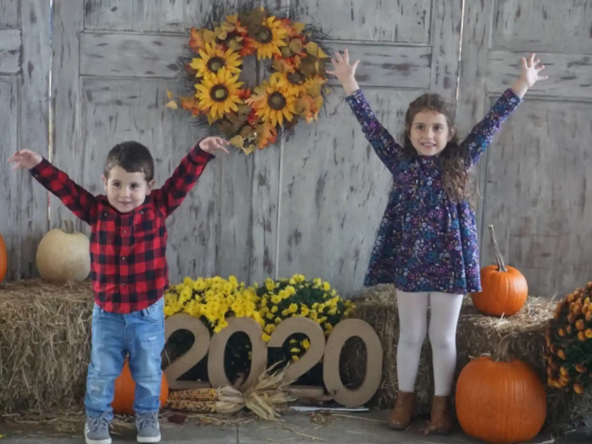 a person and a boy posing for a picture with pumpkins and flowers