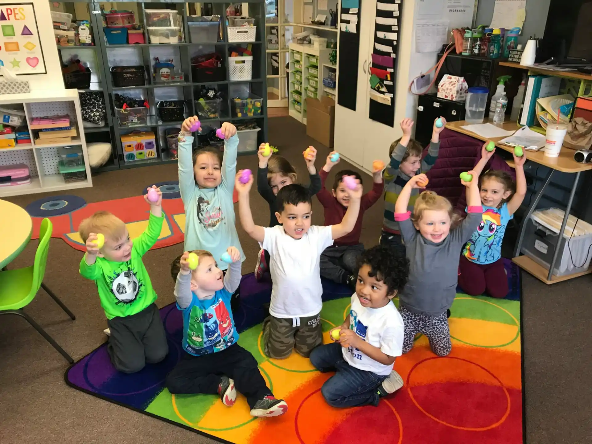 a group of children sitting on the floor with their arms up