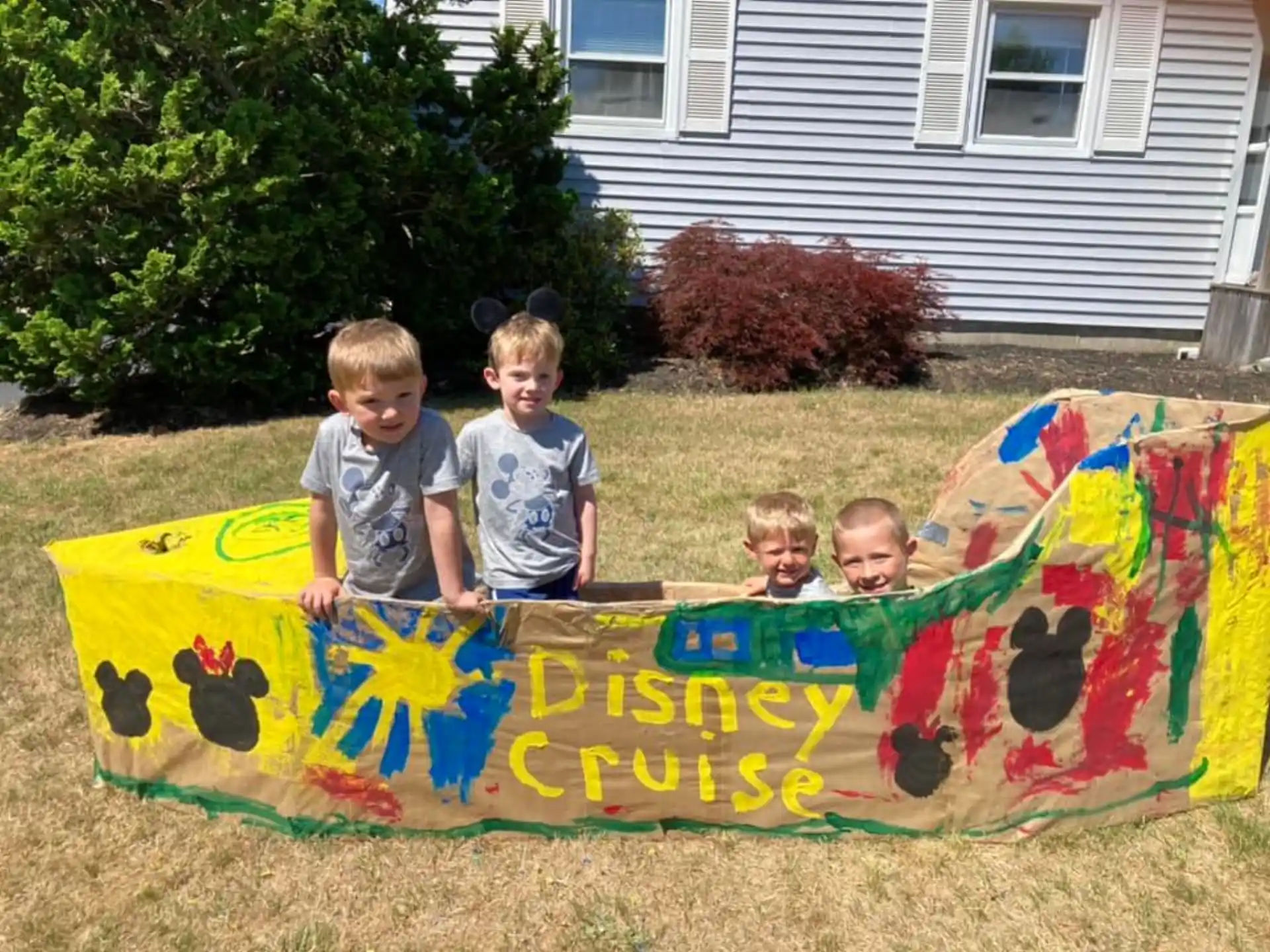 a group of kids sitting on a sign in front of a house