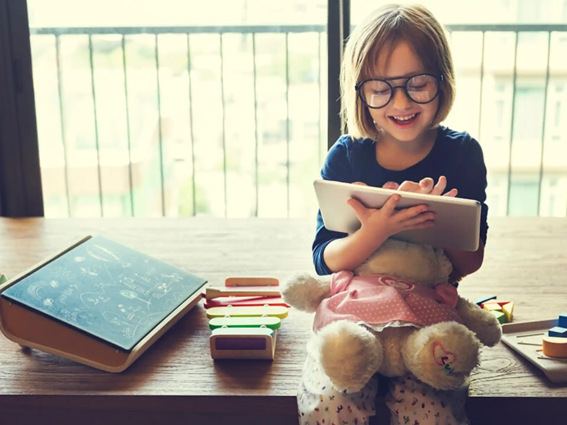 a girl sitting at a table with a book and a stuffed animal