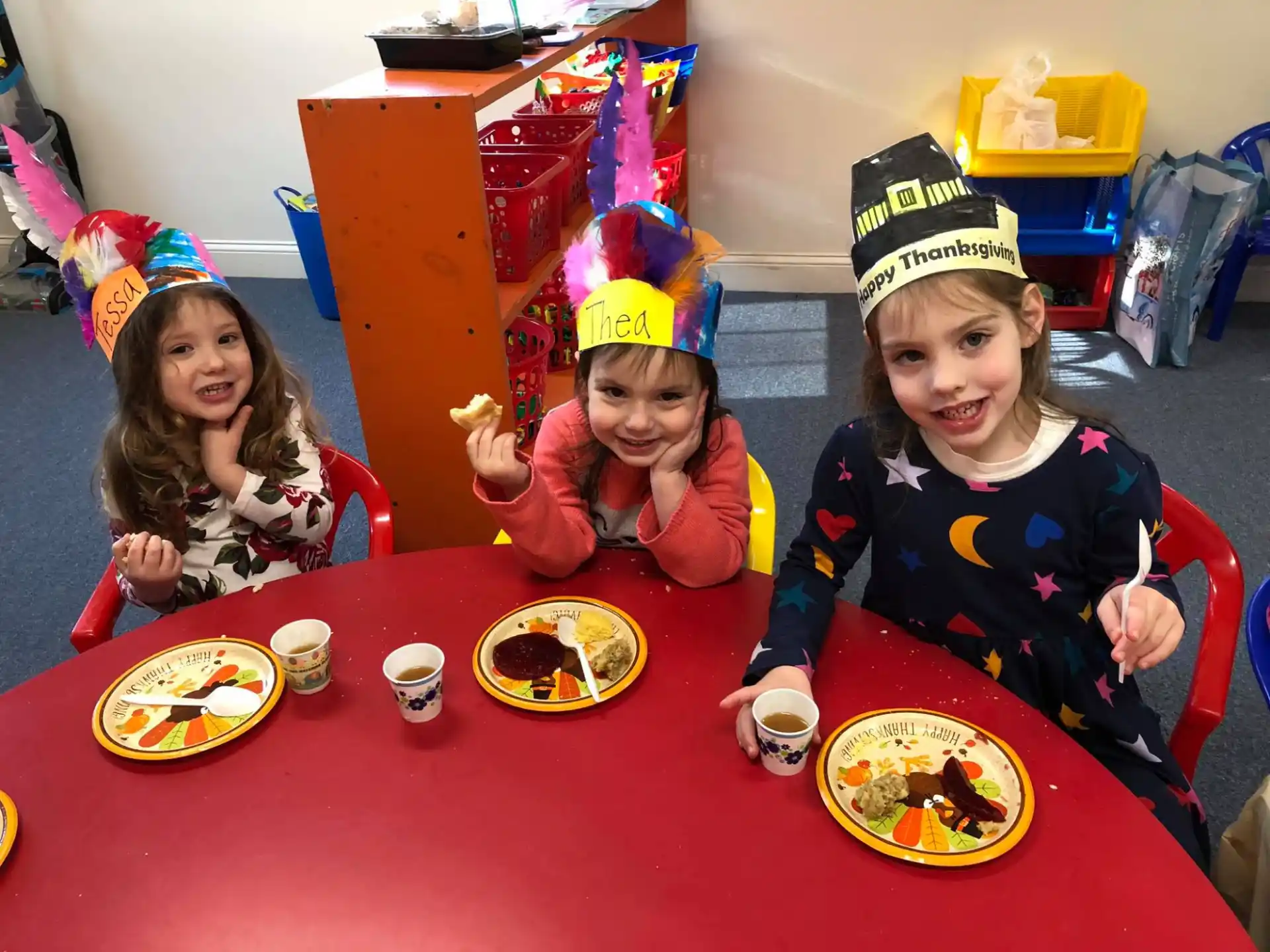 a group of kids sitting at a table eating food