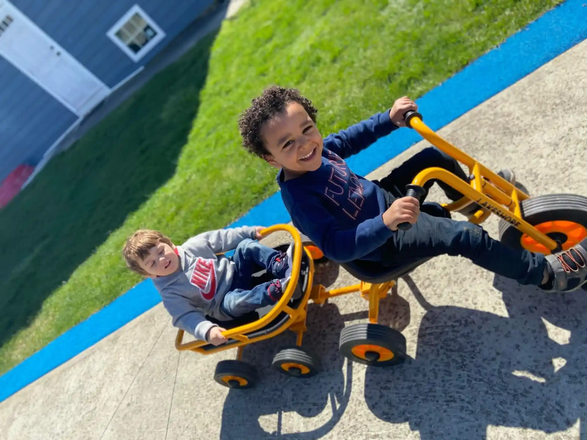 a couple of boys playing on a toy tricycle