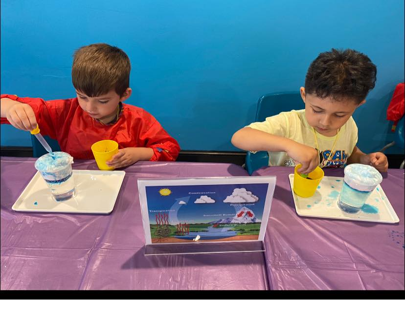 a couple of boys sitting at a table with a game on it