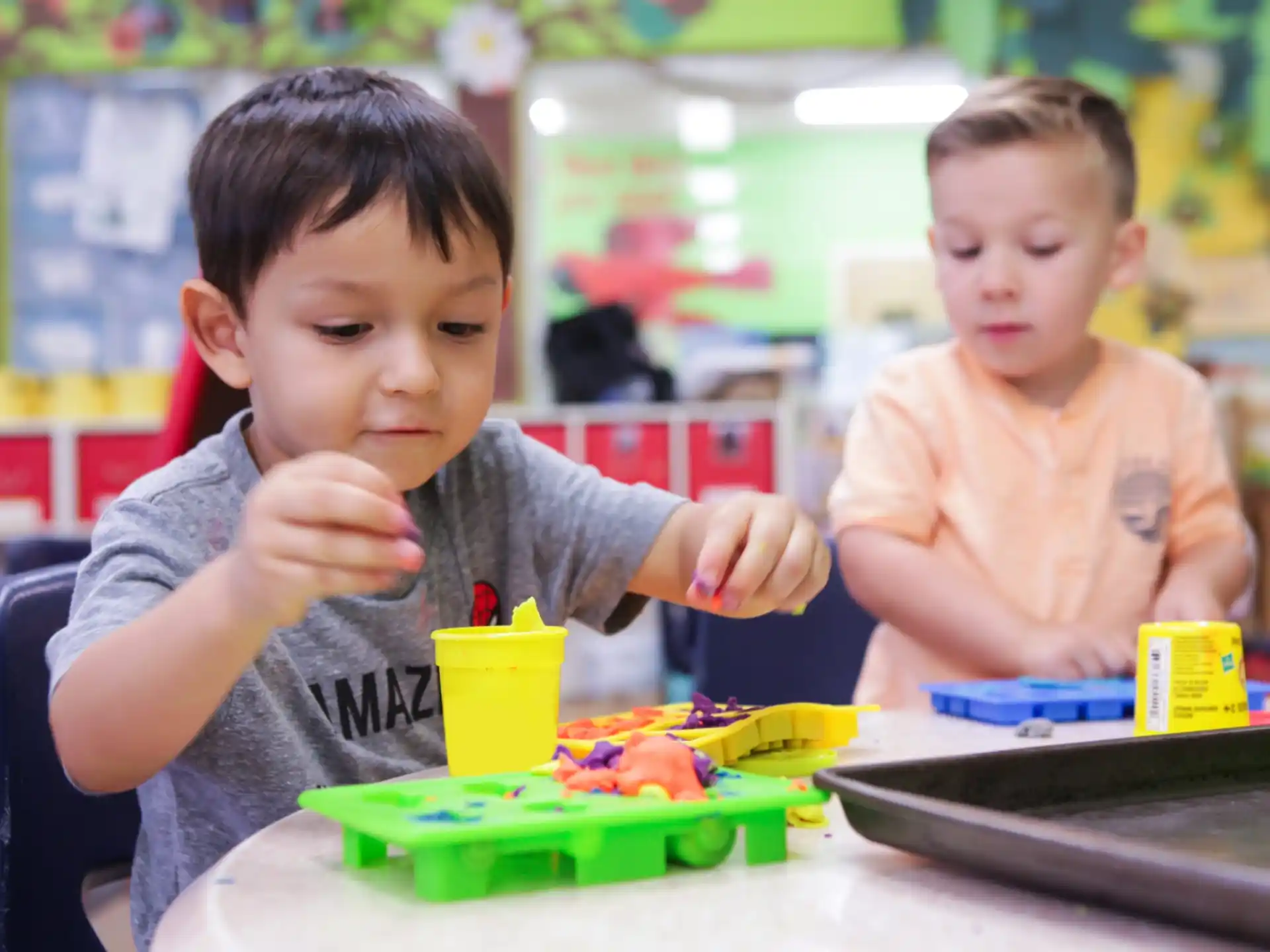 a couple of boys sitting at a table with a toy