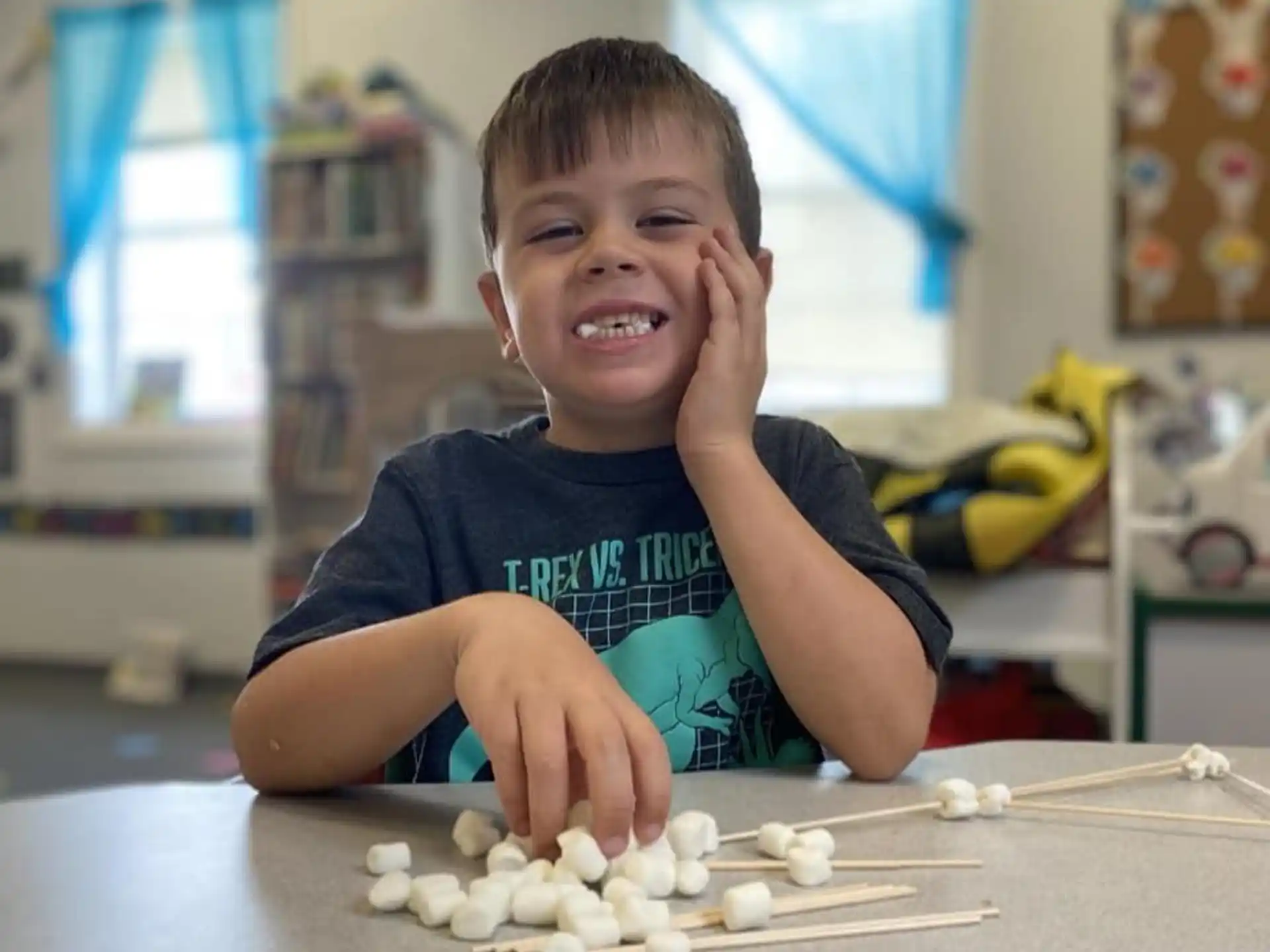 a boy sitting at a table with a pile of white objects