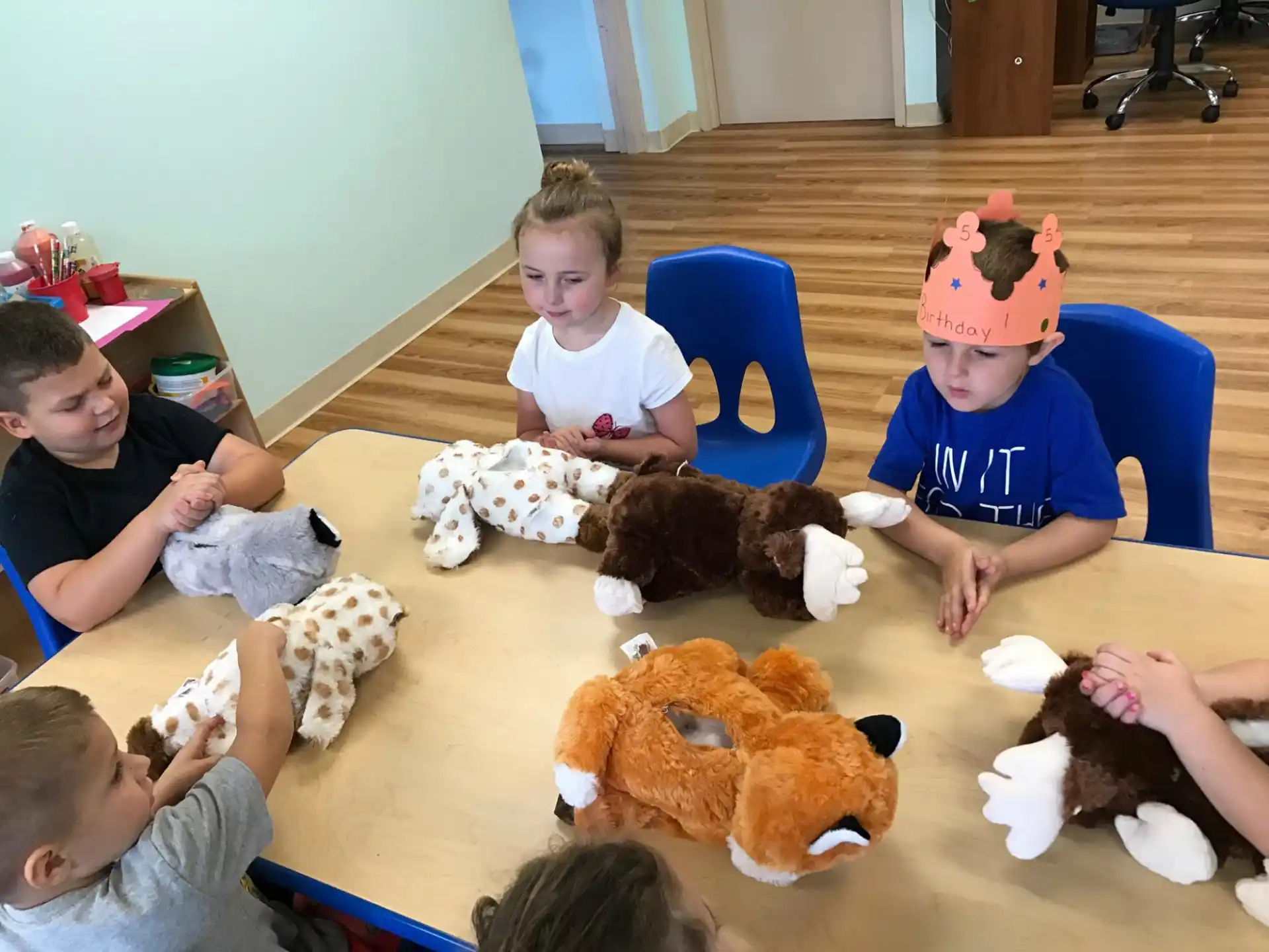 a group of children sitting on the floor with stuffed animals
