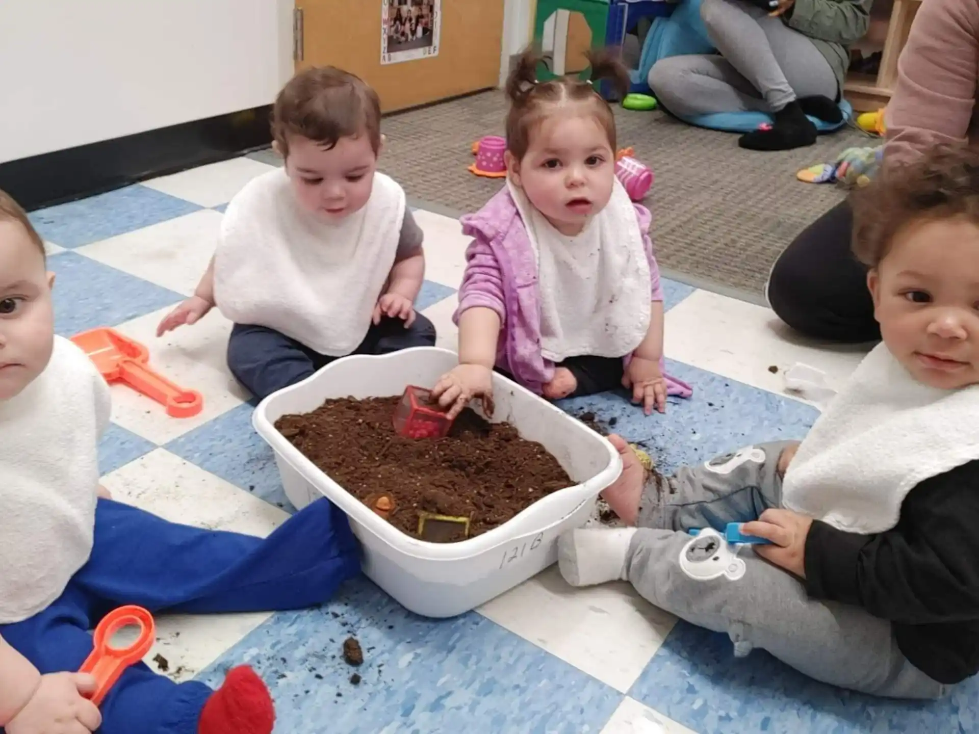 a group of children sitting on the floor with a bowl of food