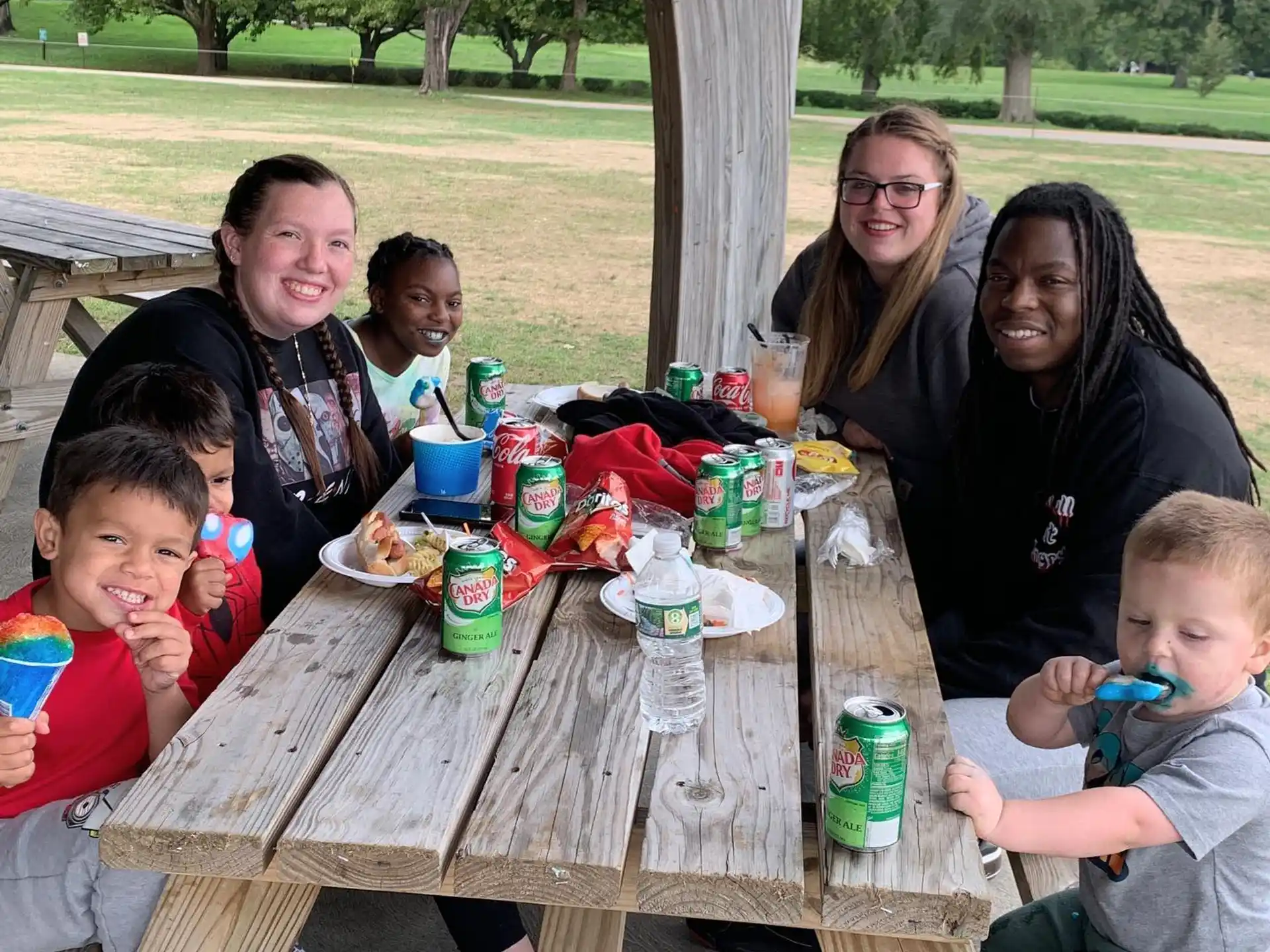 a group of people sitting around a table with food and drinks