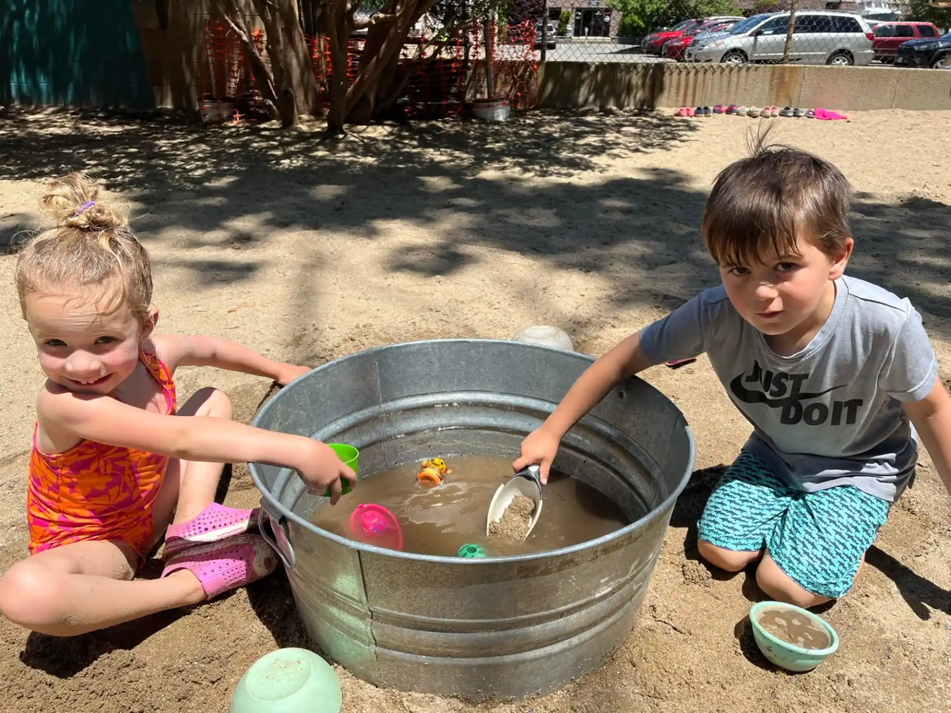 a couple of children playing in a bucket of water