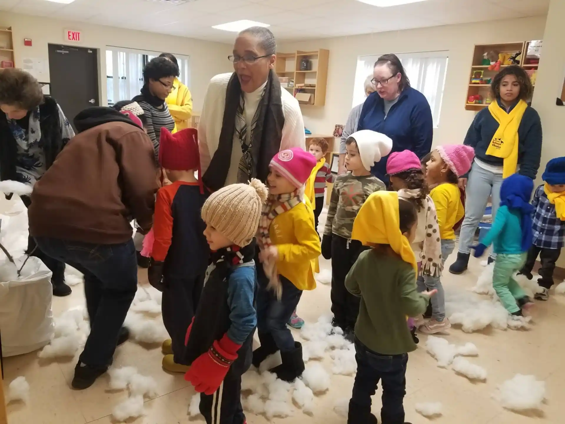 a group of people standing in a room with a person and a group of children