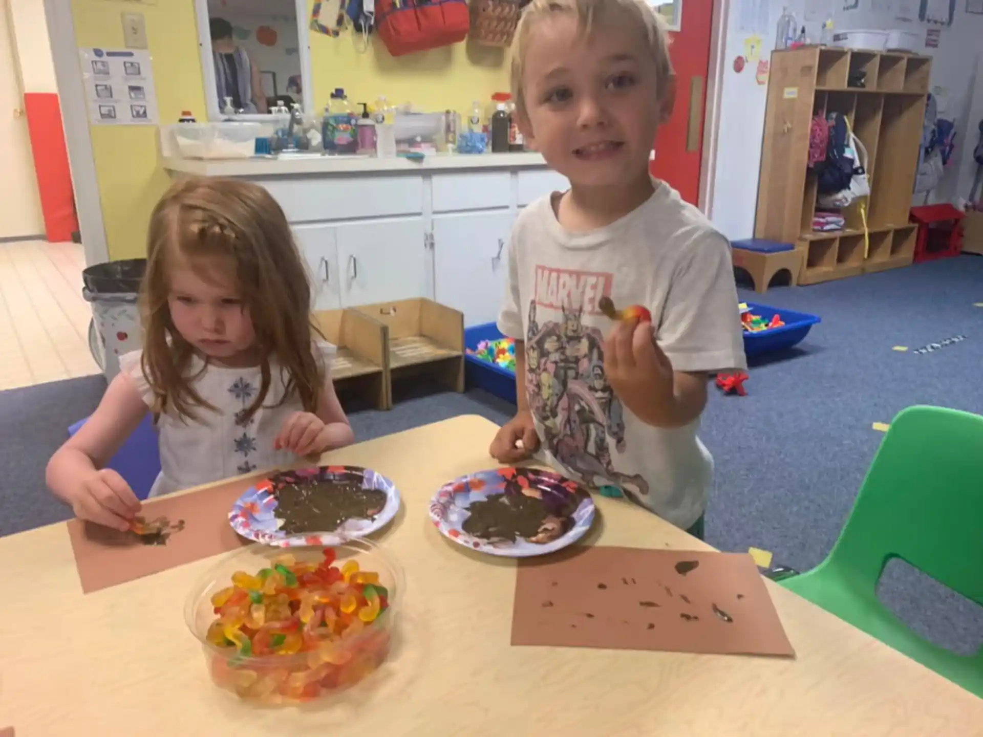 a couple of kids sitting at a table with food on it