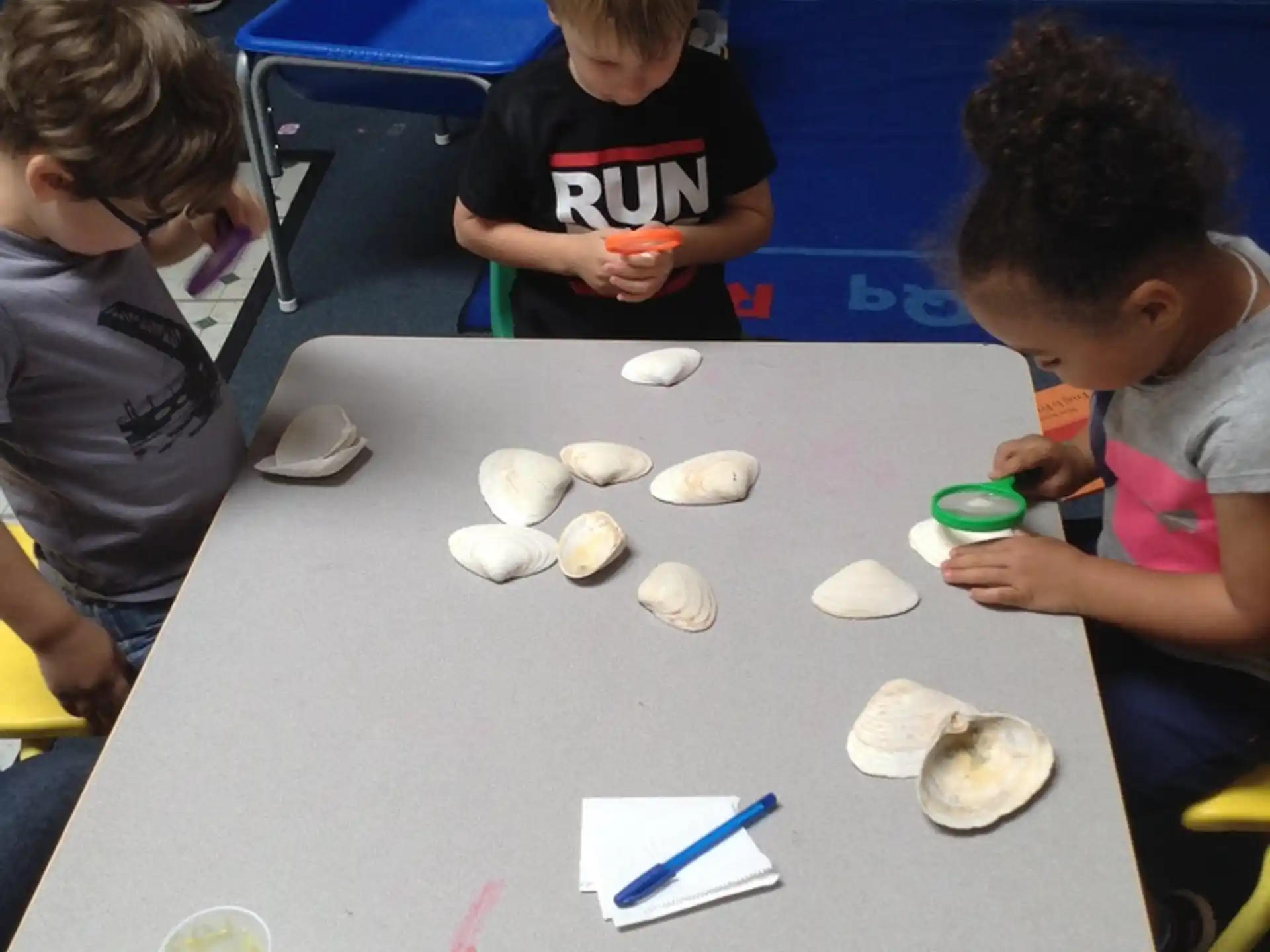a group of children sitting at a table playing with white balls