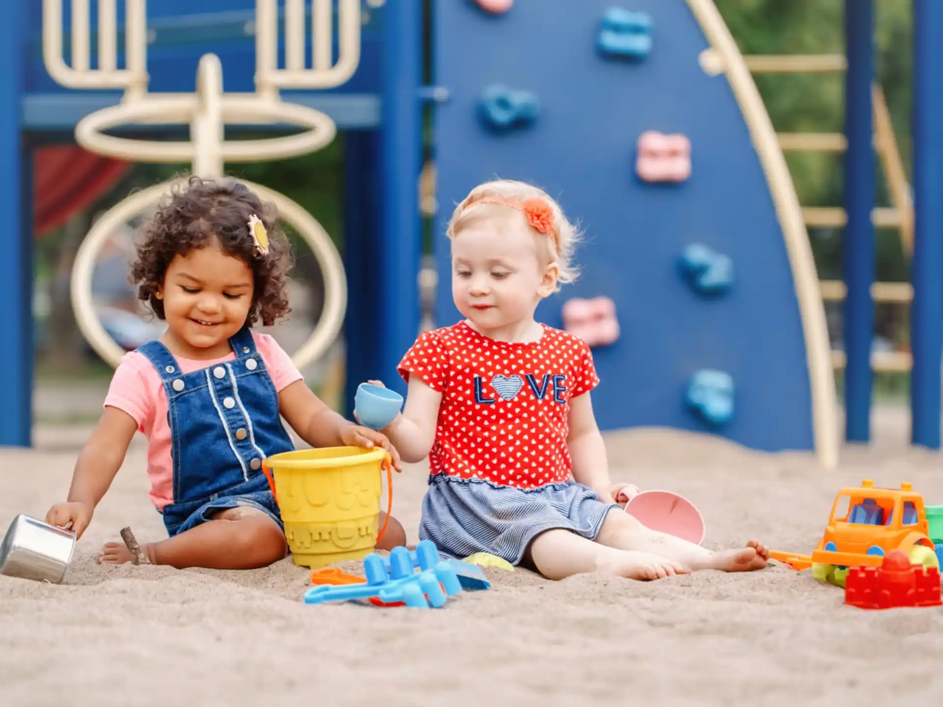 a couple of young girls playing in the sand