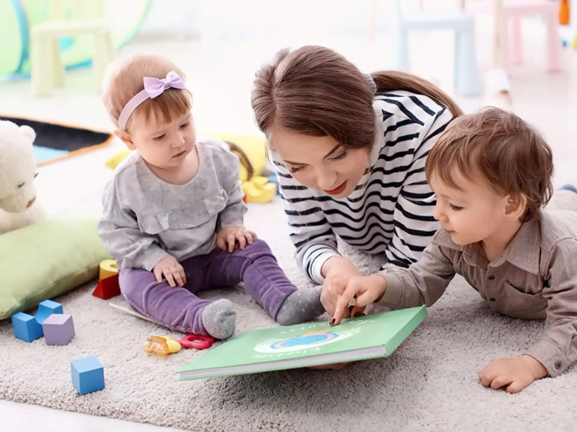 a person and two children playing on a green mat