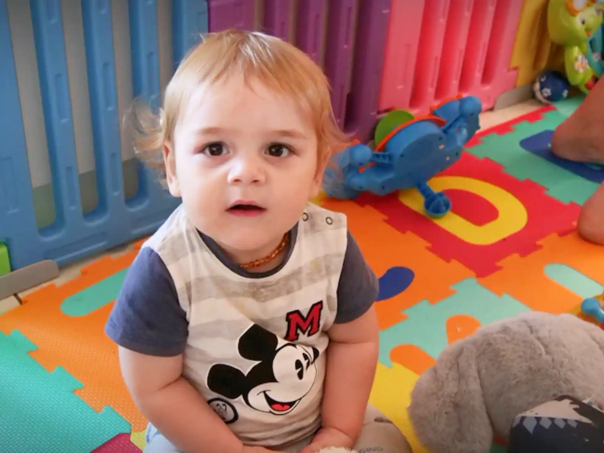 a baby sitting on a colorful floor