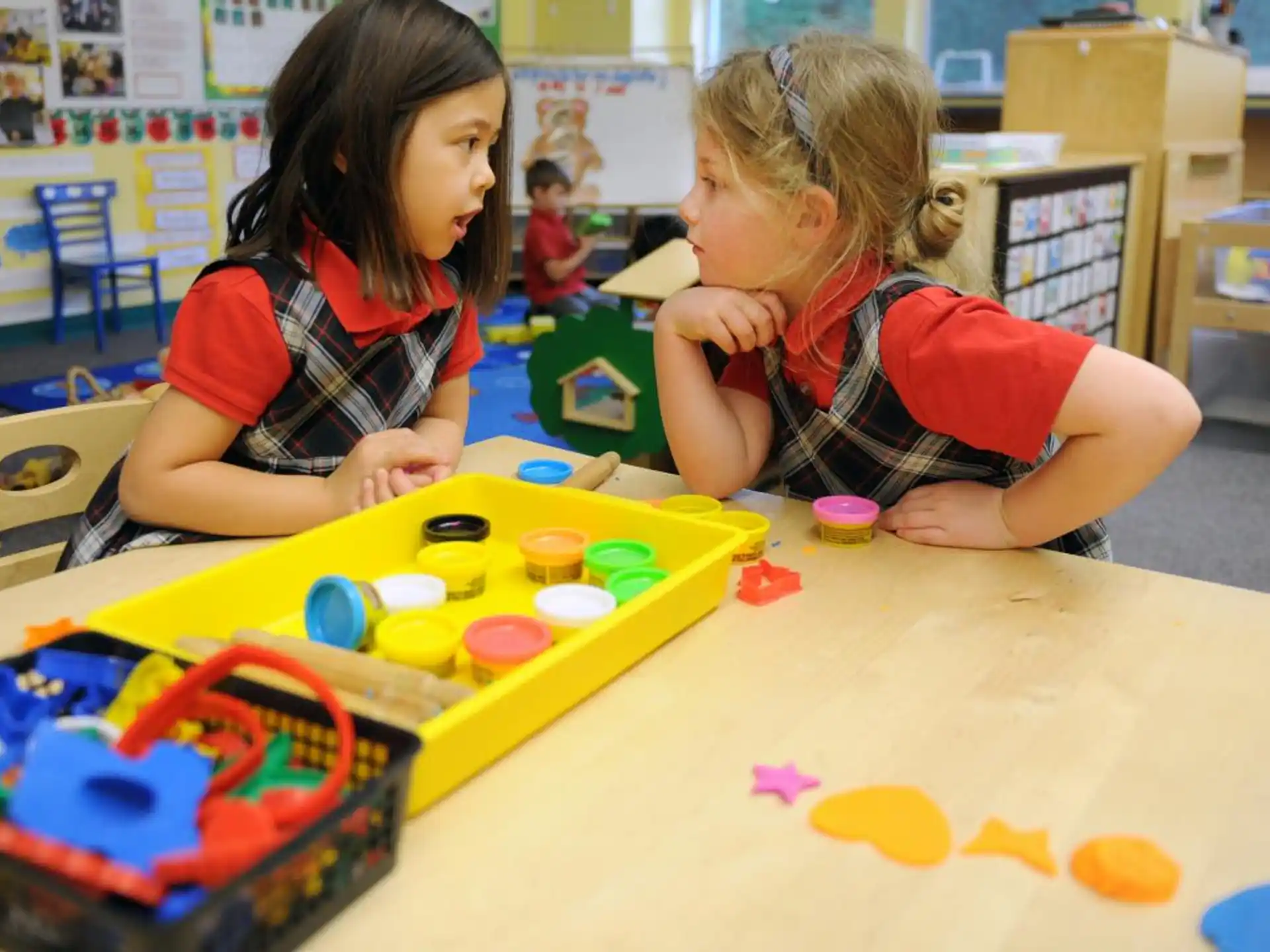 a couple of young girls playing with toys in a classroom