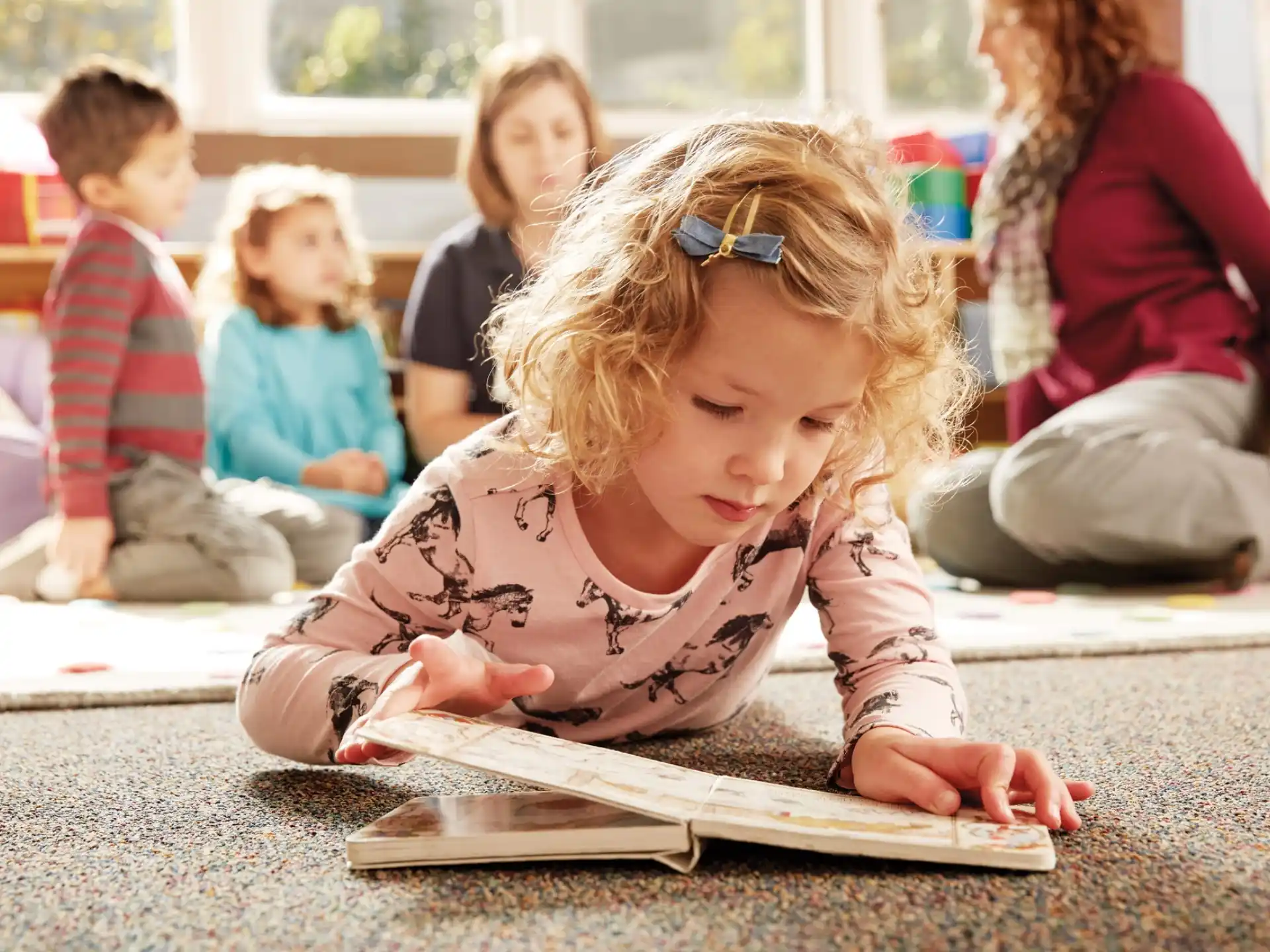 a young girl sitting on the floor reading a book