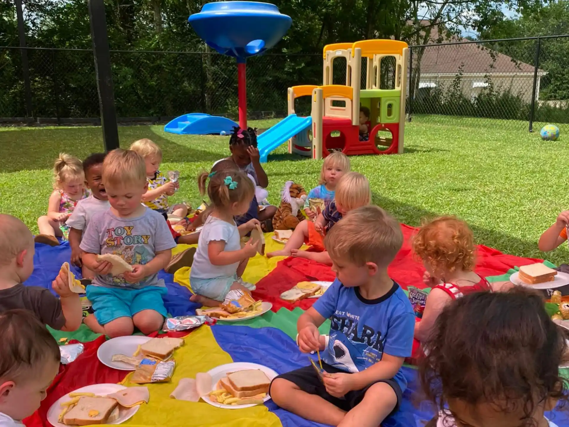a group of children sitting on a blanket on a picnic table