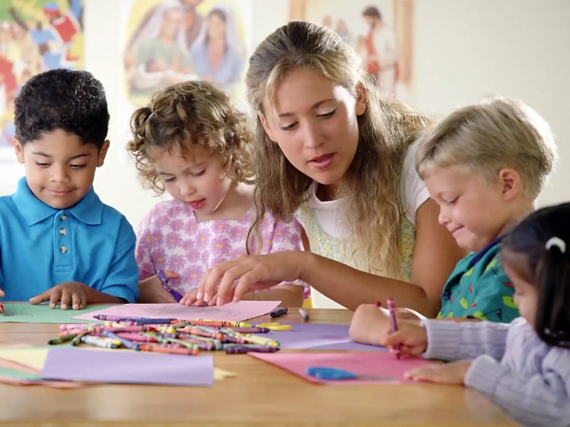 a group of children sitting at a table writing on paper
