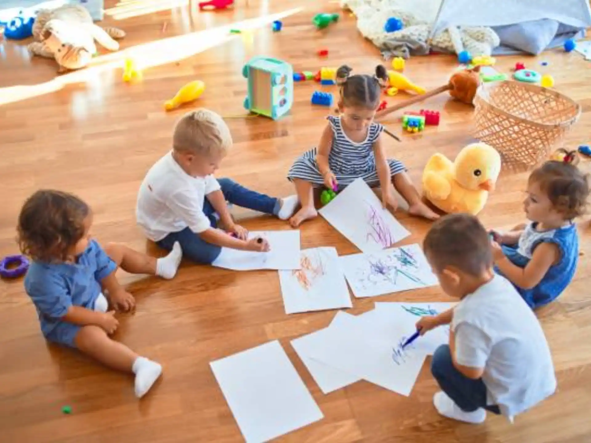 a group of children sitting on the floor with a paper and toys