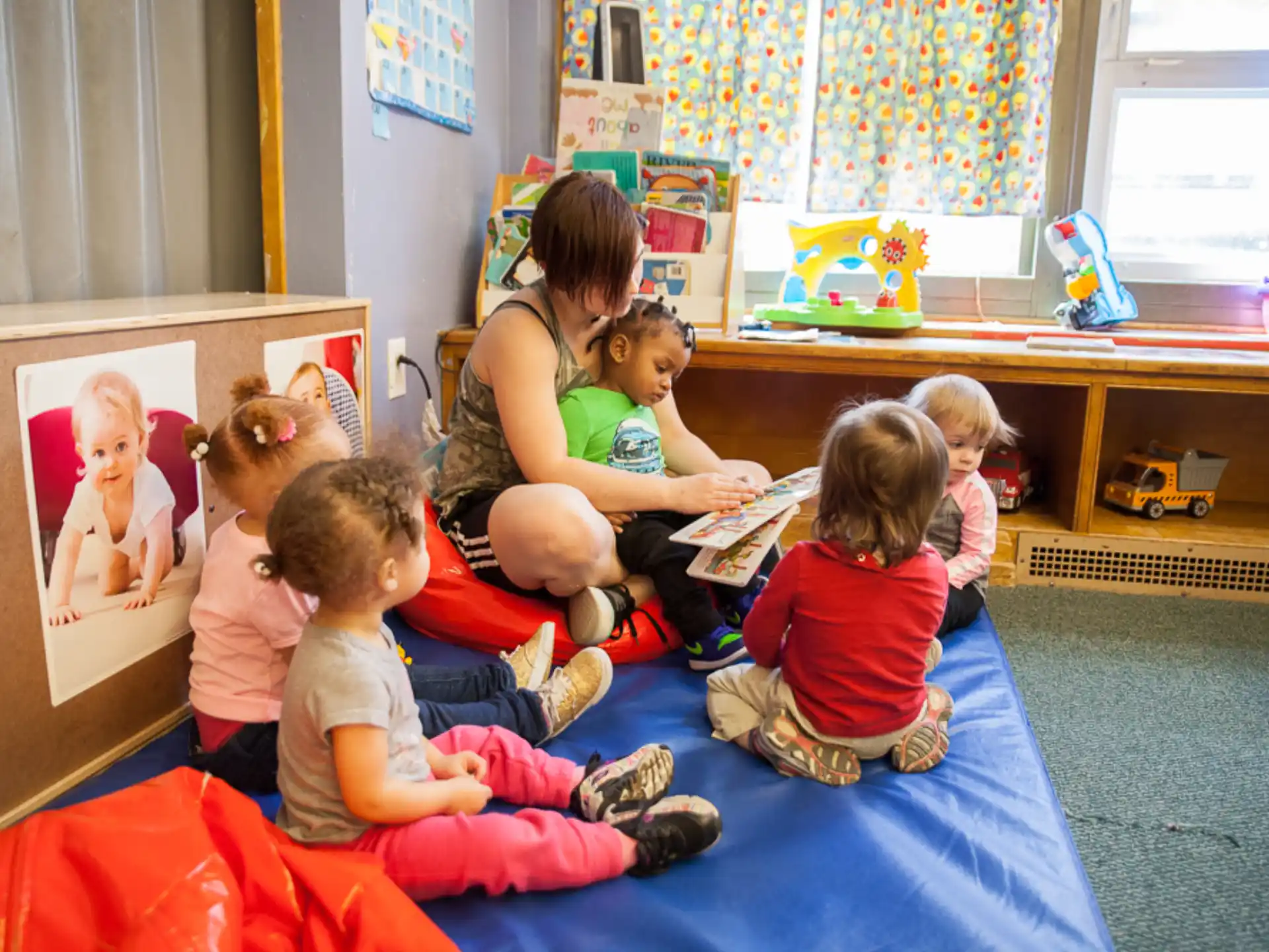 a group of children sitting on a mat in a room