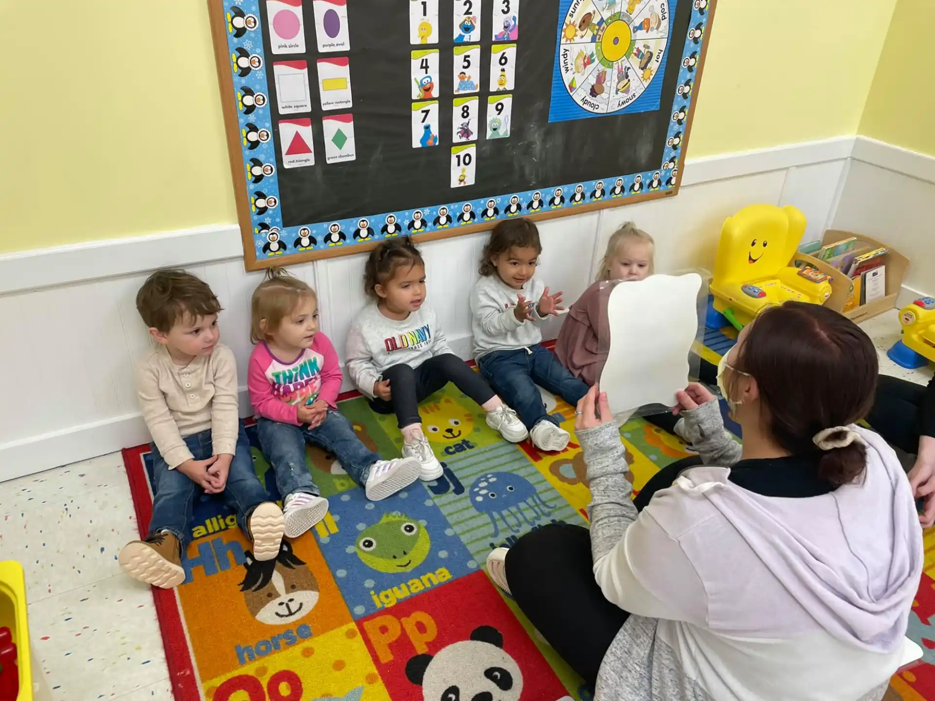 a group of children sitting on a rug in a classroom