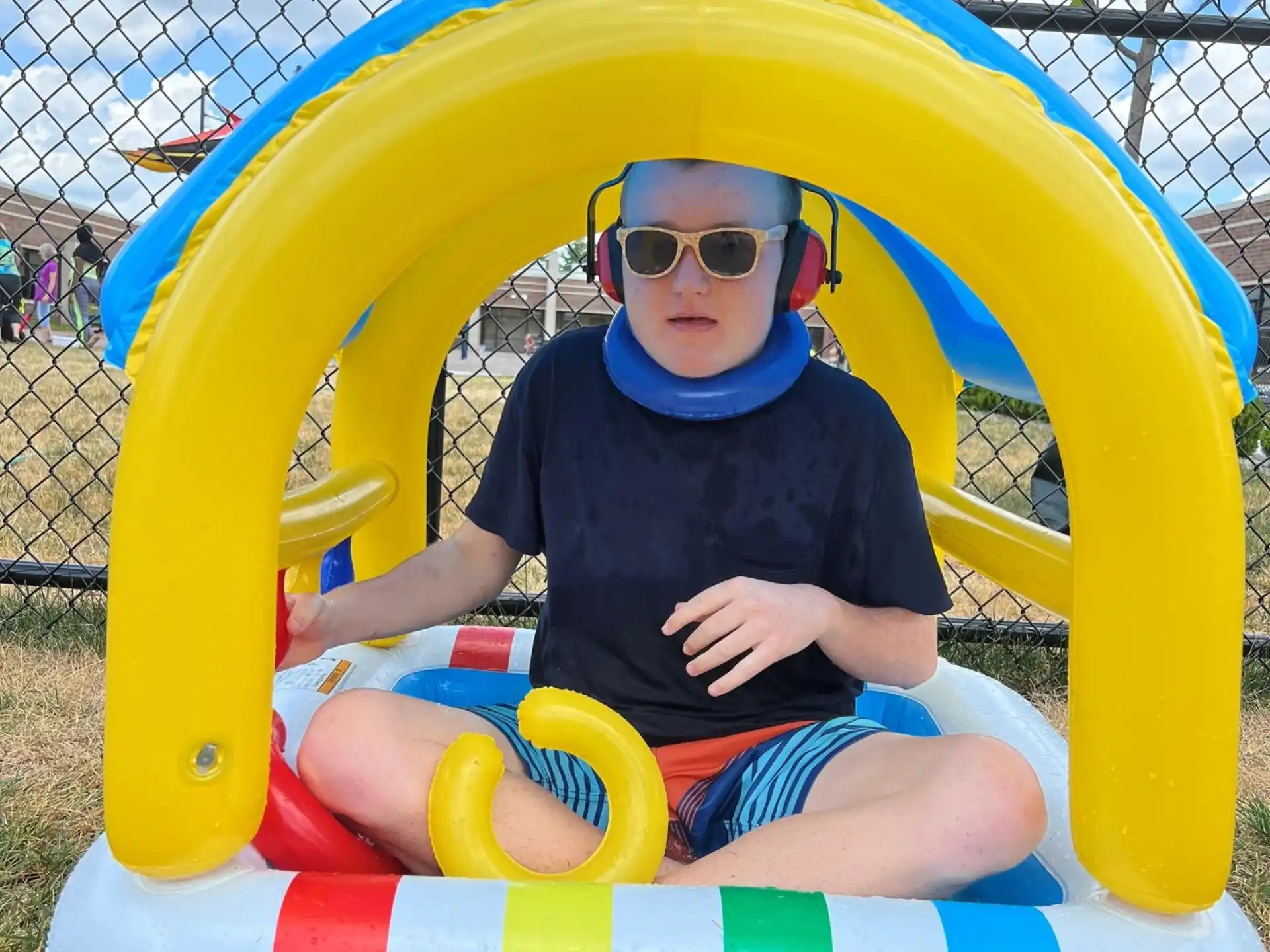 a boy sitting in a yellow and blue playground toy