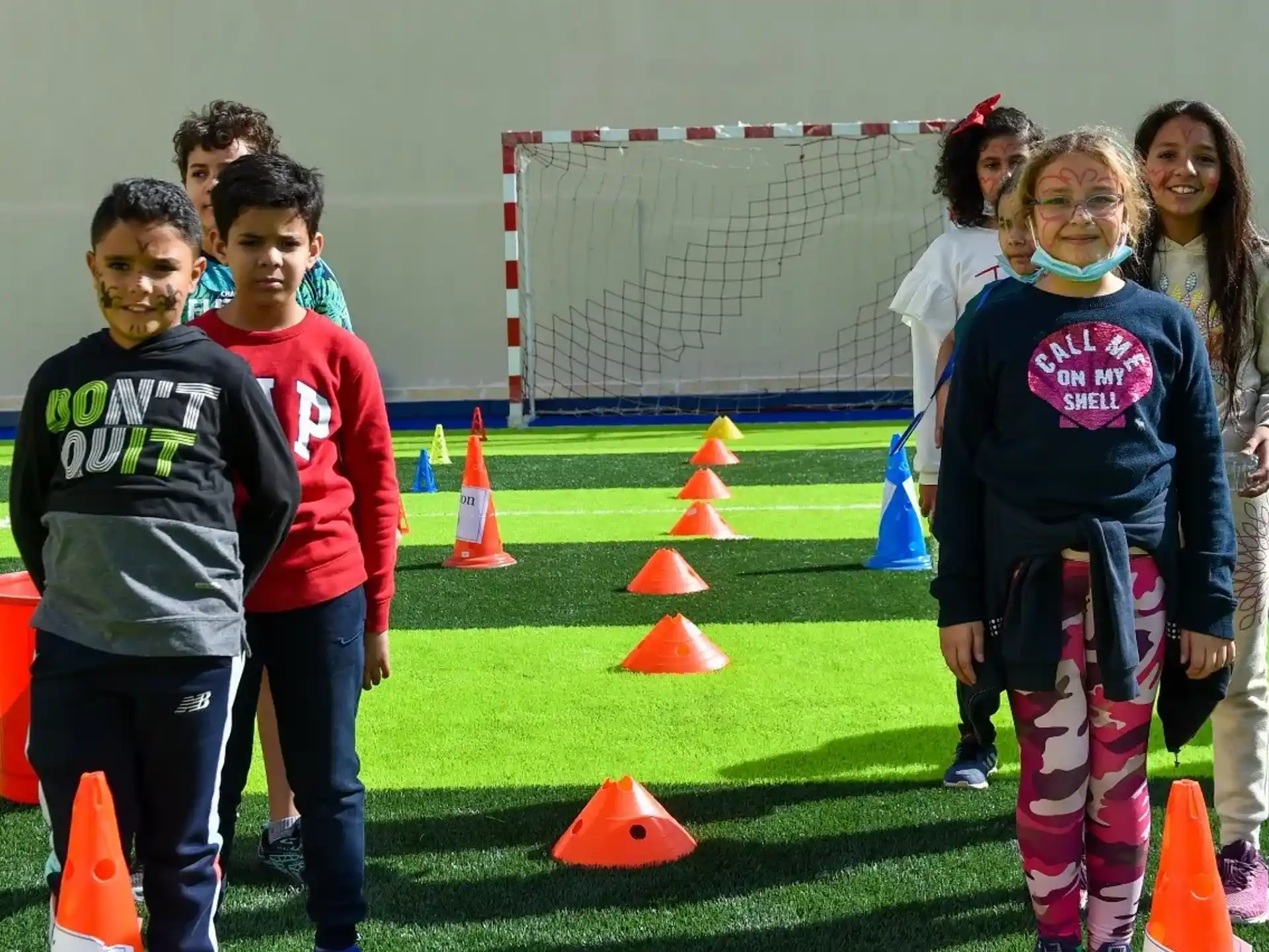 a group of people standing on a field with cones and a football goal