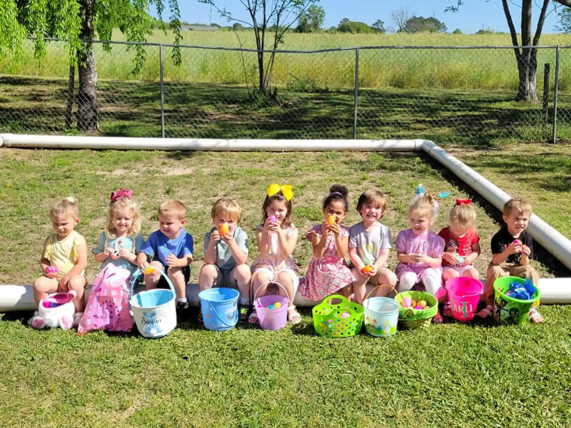 a group of children sitting on the grass with buckets