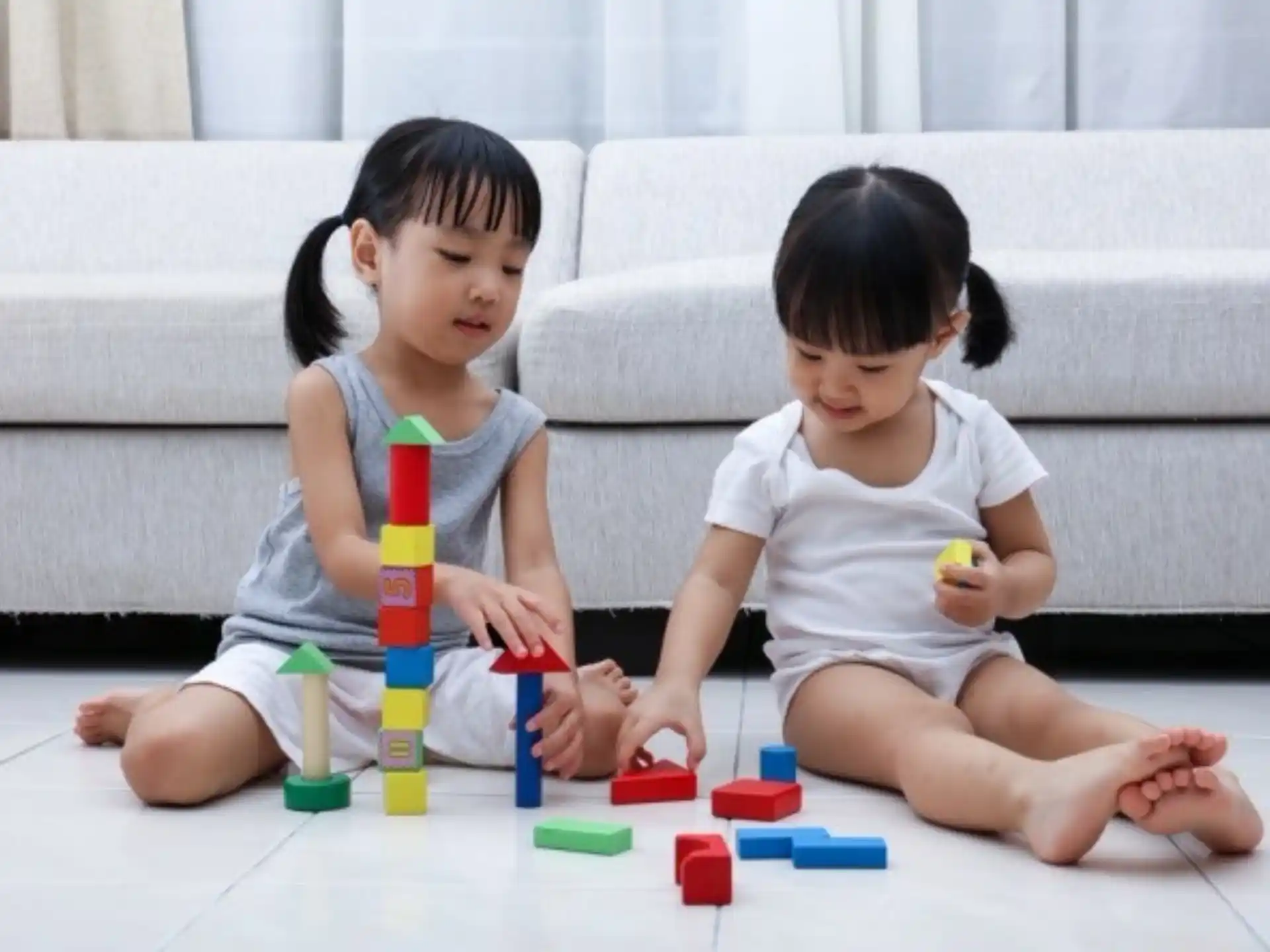 a couple of young girls playing with toys on the floor