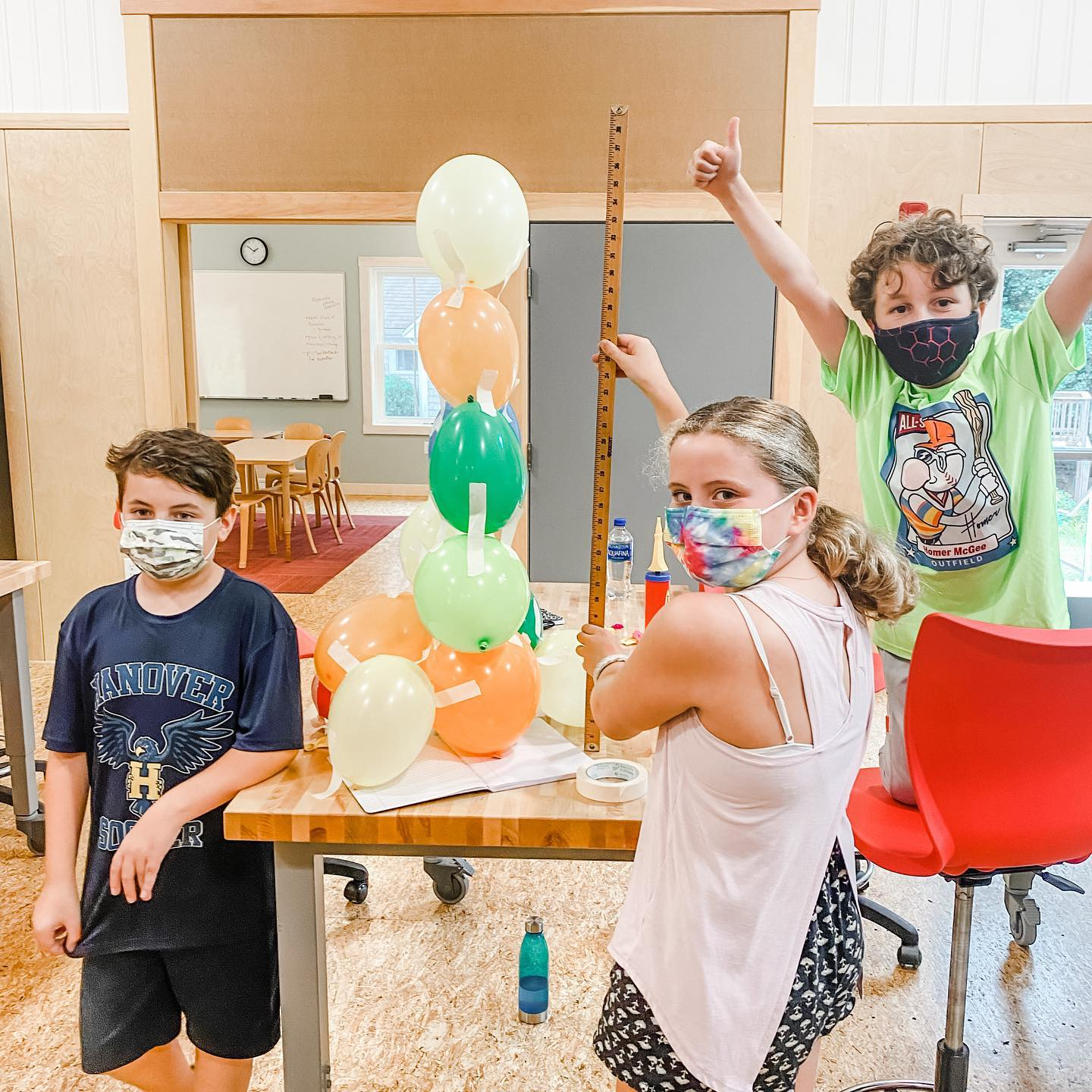 a group of kids wearing masks and holding balloons