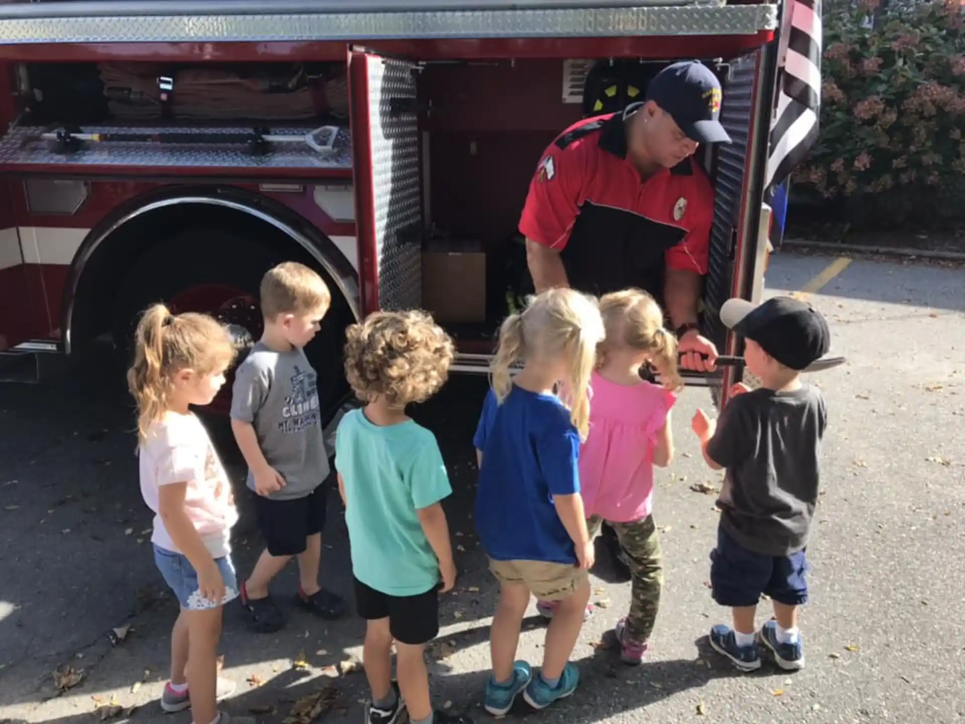 a group of children standing in front of a firetruck