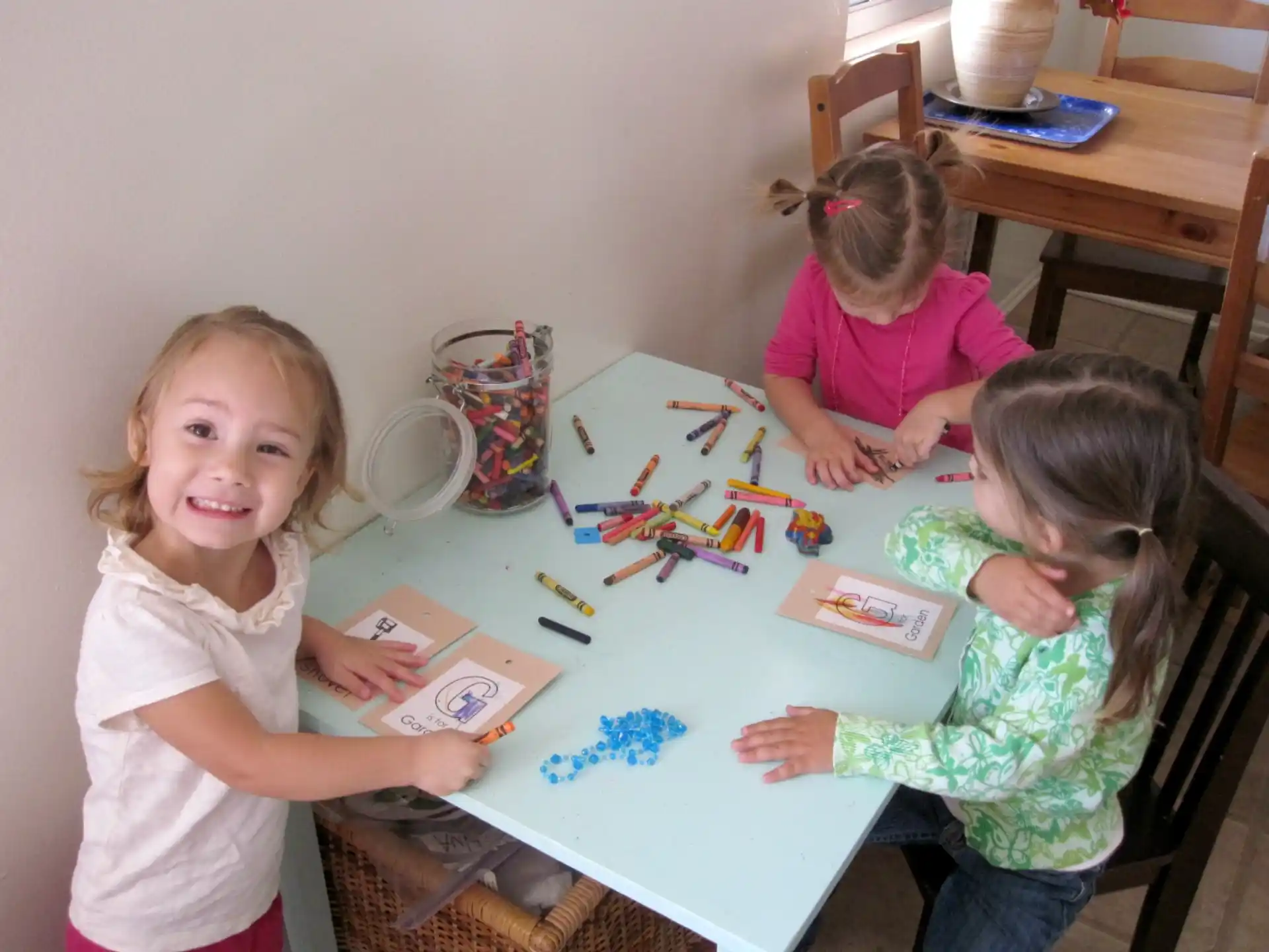 a few young girls sitting at a table with art
