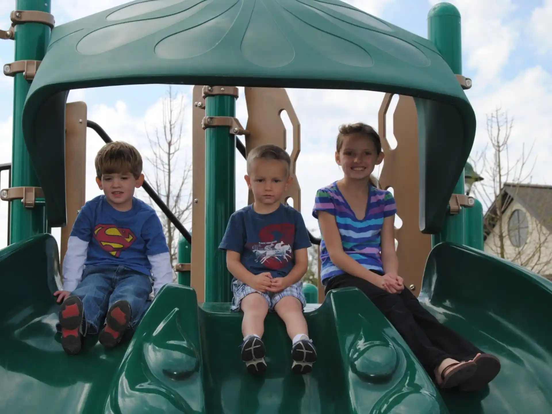 a group of kids sitting on a green amusement park ride