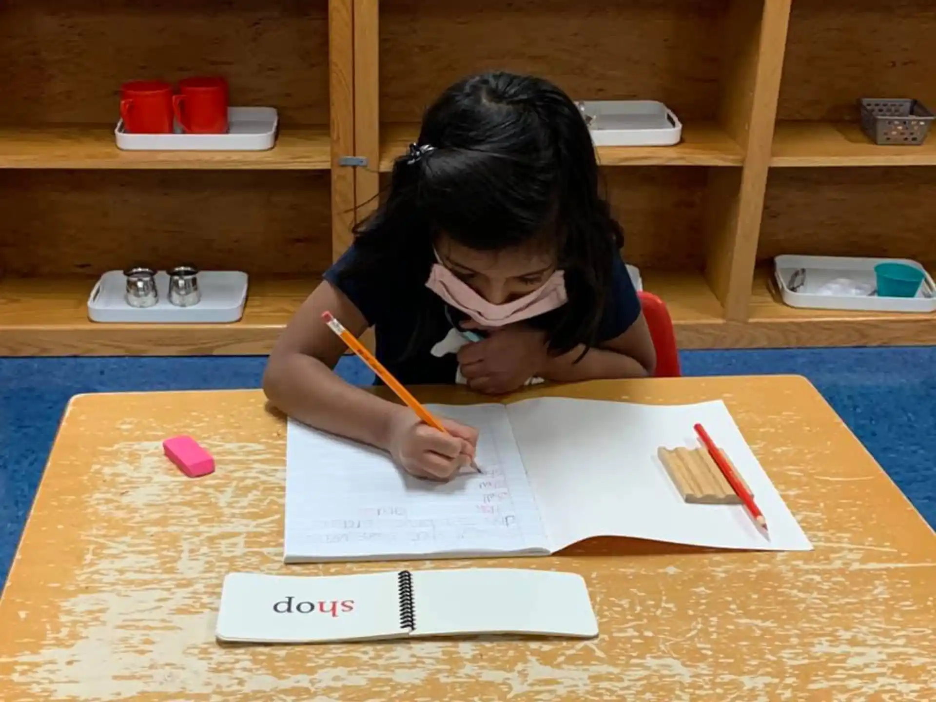 a girl sitting at a table writing on paper