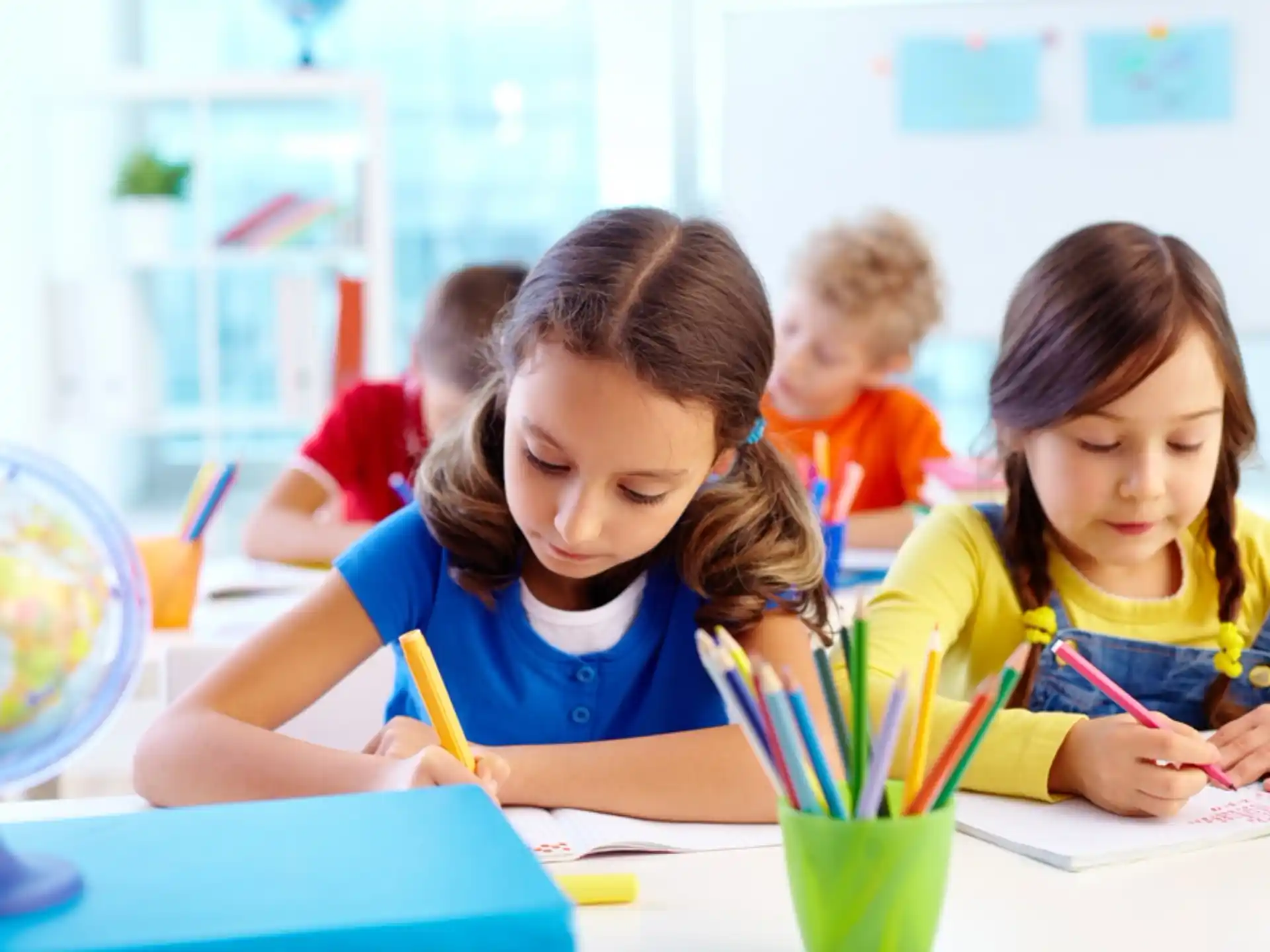 a group of children sitting at a table writing on paper