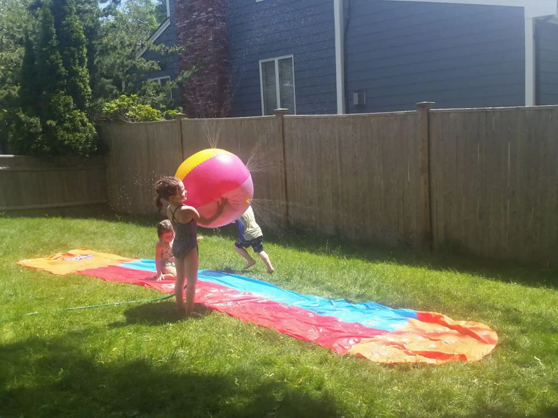 a group of kids playing in a yard with a large colorful slide