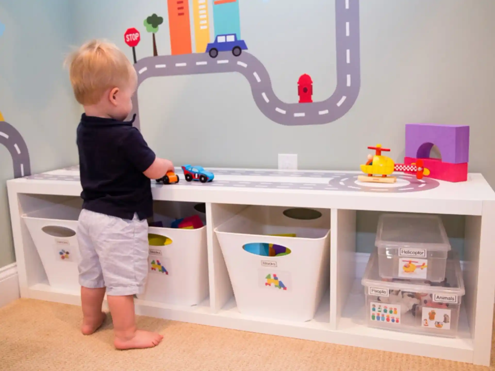 a child standing in front of a white shelf with toys on it