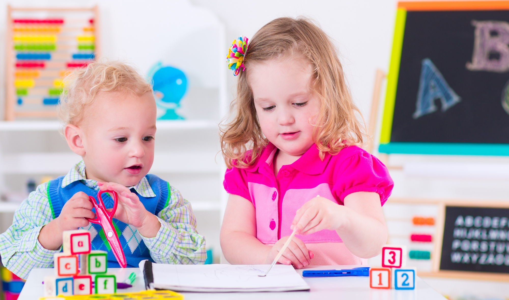 a couple of children sitting at a table with a toy