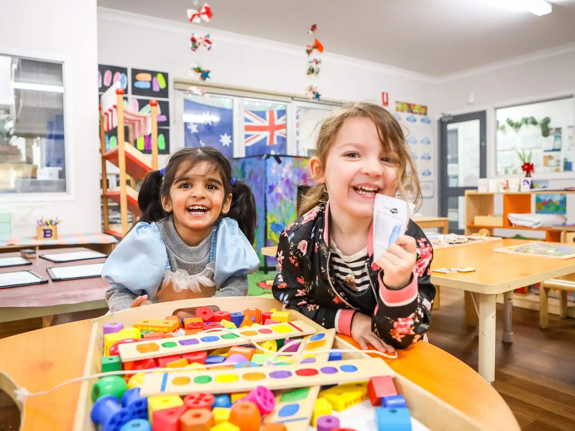 a couple of girls sitting at a table with a board game
