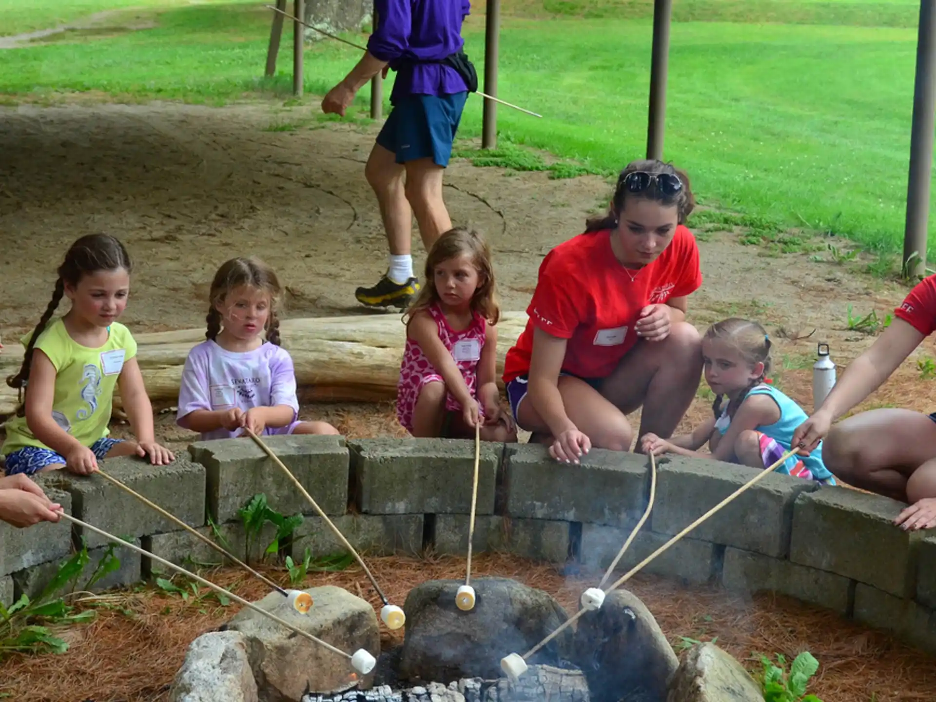 a group of children sitting around a fire pit