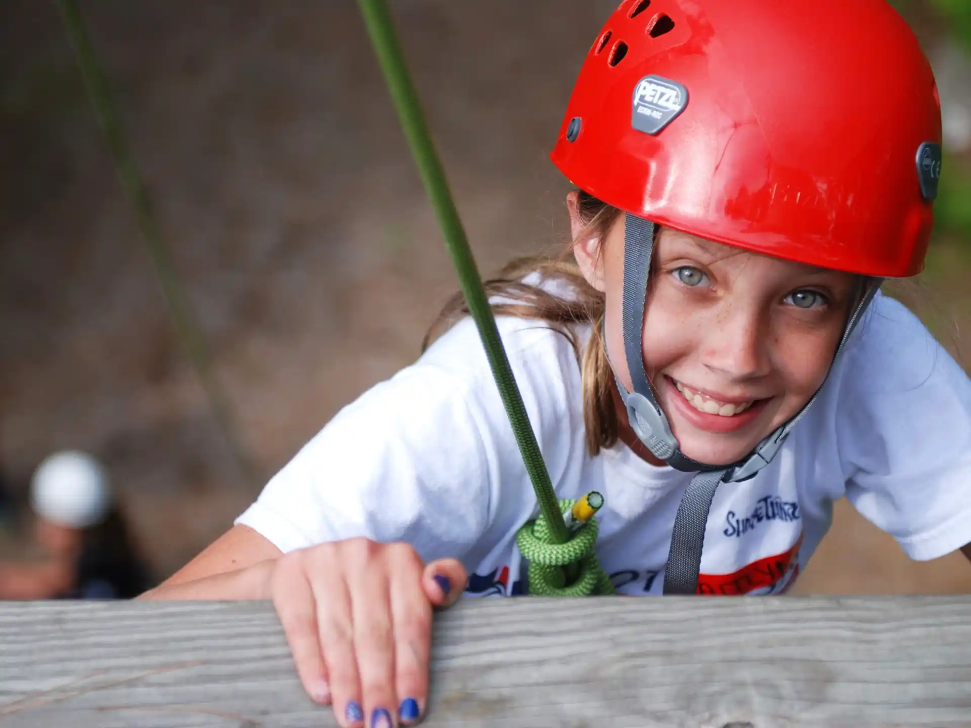 a young girl wearing a helmet and holding a green plant