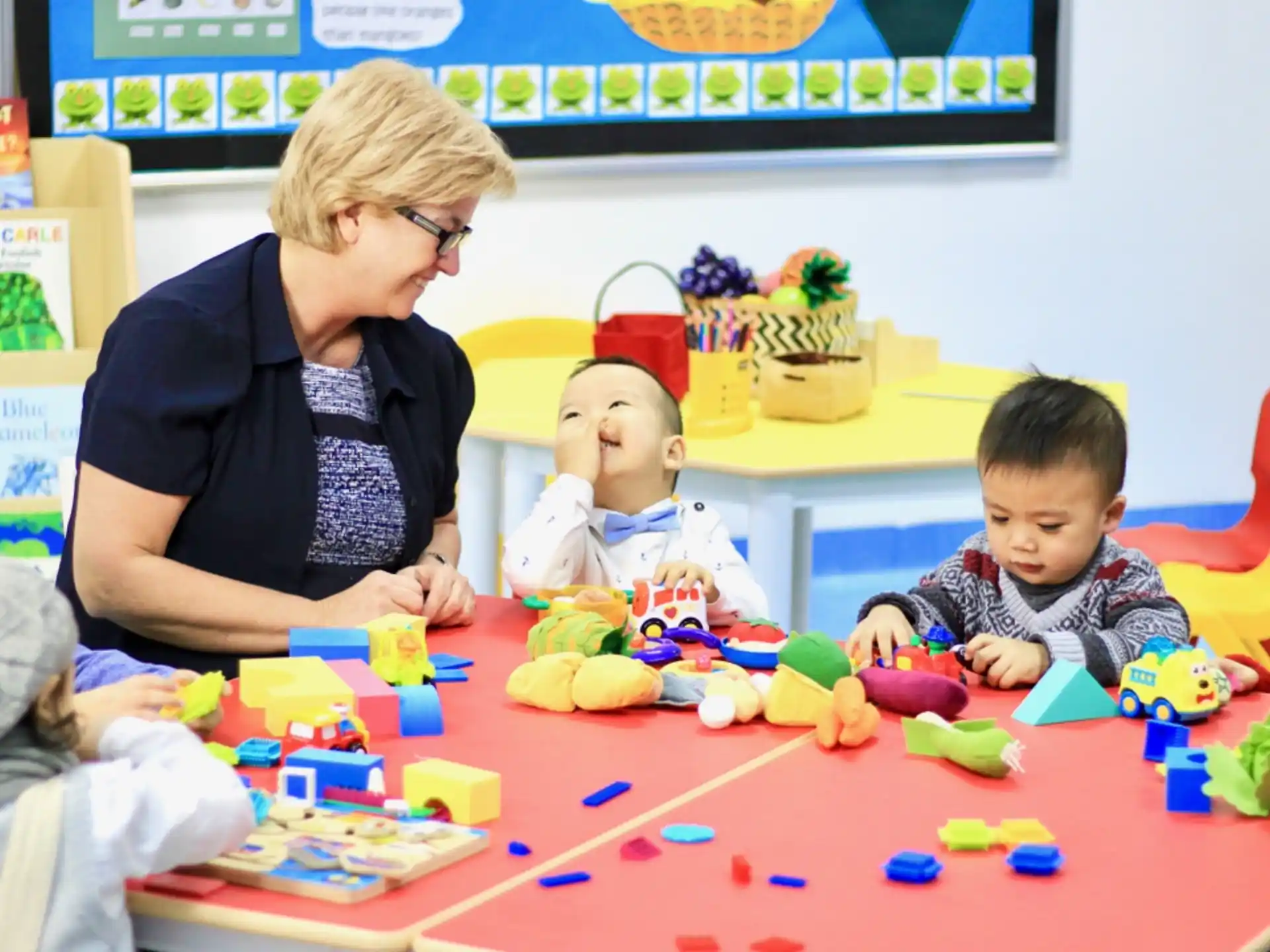 a person and several children playing with toys on a table