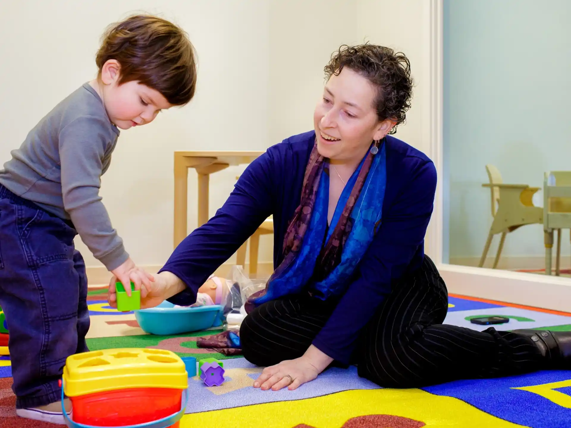 a woman and a boy playing with toys on a table