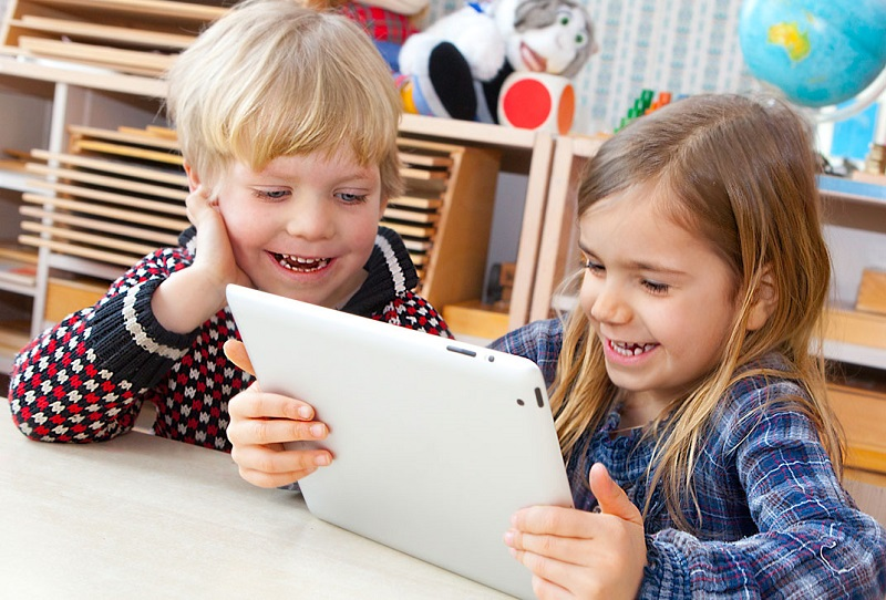 a couple of children looking at a tablet