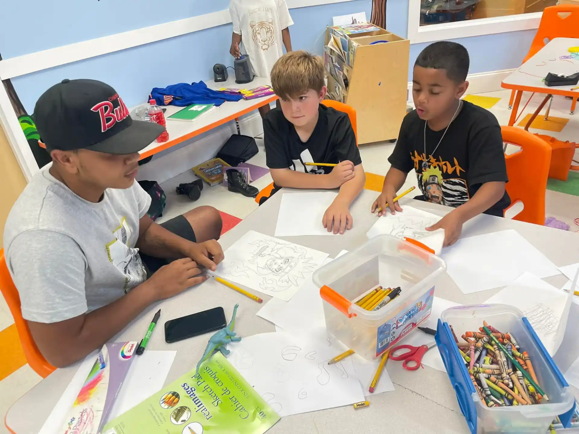 a group of boys sitting at a table with a white board